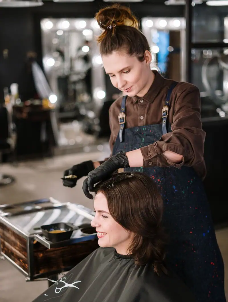 Cabeleireira finalizando o cabelo de uma cliente